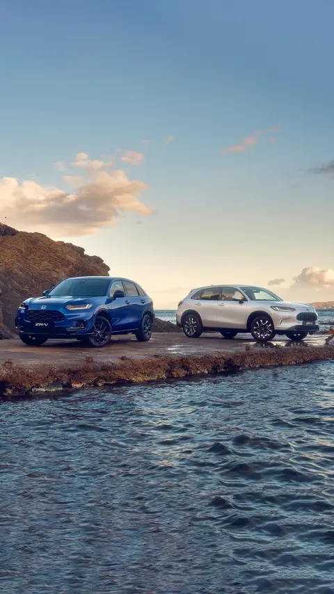 To ZR-V Hybrid-biler set skråt forfra, mens de er parkeret i et bjergrigt område.